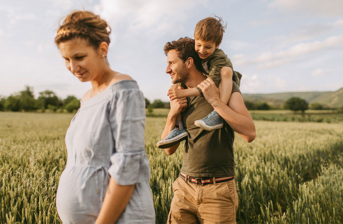Kinderabsicherung von AXA Pärchen auf dem Feld spazieren mit Kind