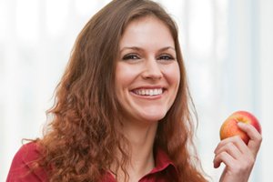 AXA Bremen fair Finanzpartner oHG | Zahnzusatzversicherung AXA Bremen fair Finanzpartner oHG | Zahnzusatzversicherung Frau lacht mit Apfel in der Hand