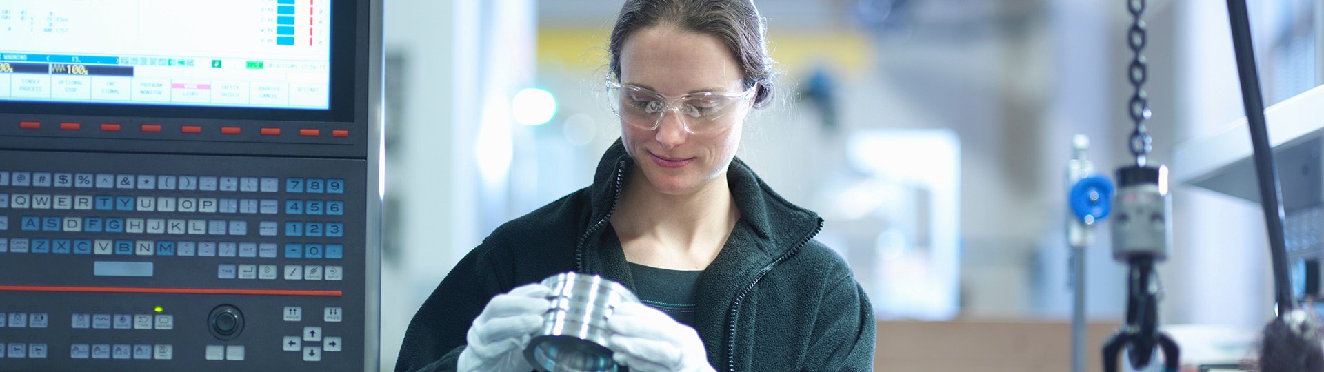 Maschinenversicherung Frau prüft Werkstück