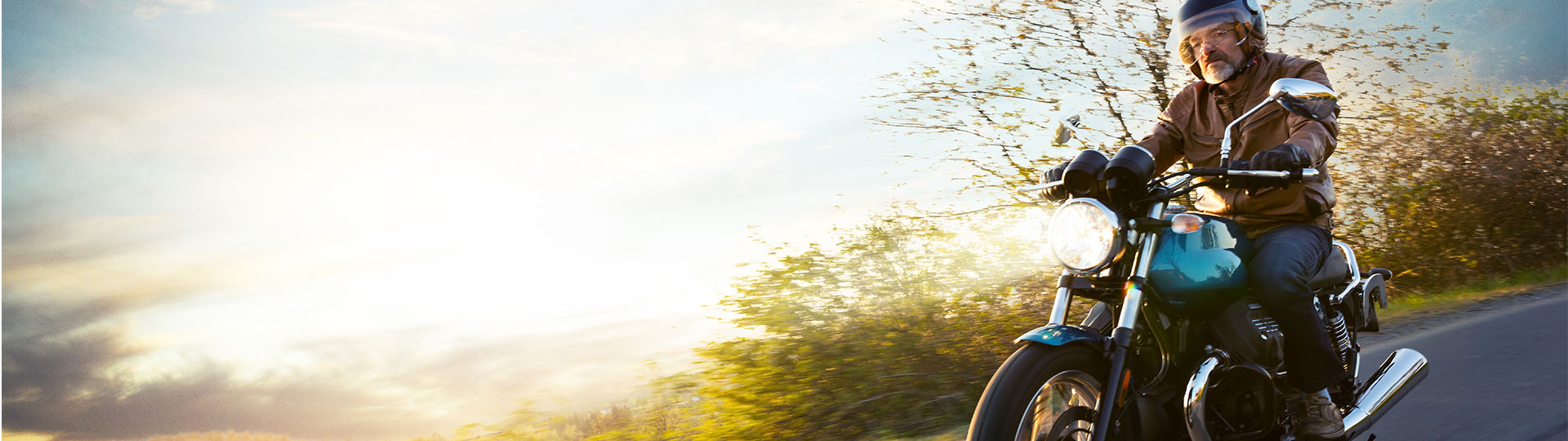 Mann fährt auf einem Motorrad entlang der Natur