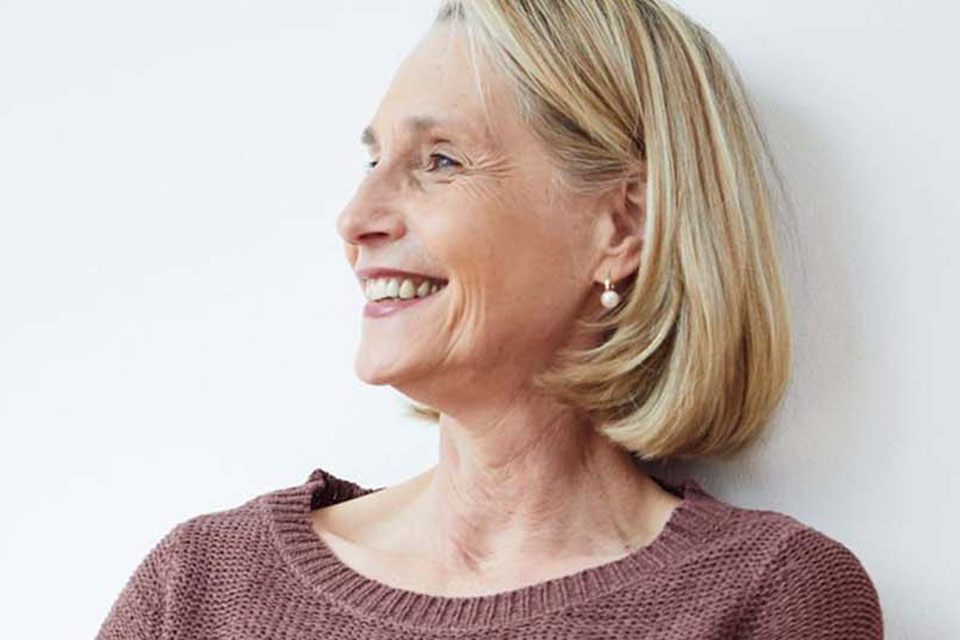 L&auml;chelnde Frau sitzt auf Fu&szlig;boden