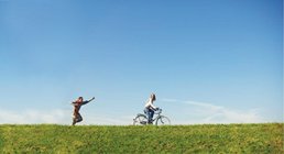 AXA Bremen fair Finanzpartner oHG | Übersicht Pärchen mit einem Fahrrad auf Wiese AXA Bremen fair Finanzpartner oHG | Übersicht Pärchen mit einem Fahrrad auf Wiese
