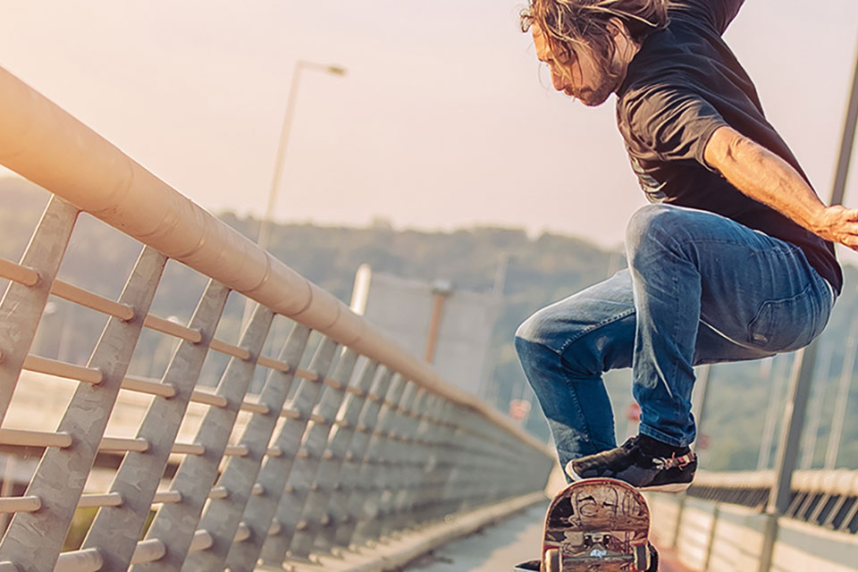 Skater macht Kunststücke auf dem Gehweg einer Brücke