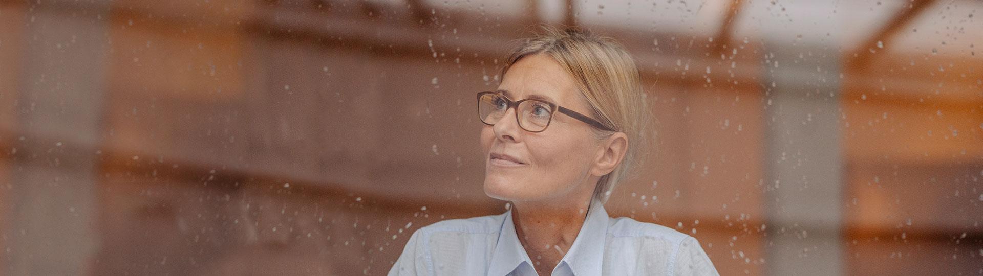 Eine Frau sitzt nachdenklich am Fenster
