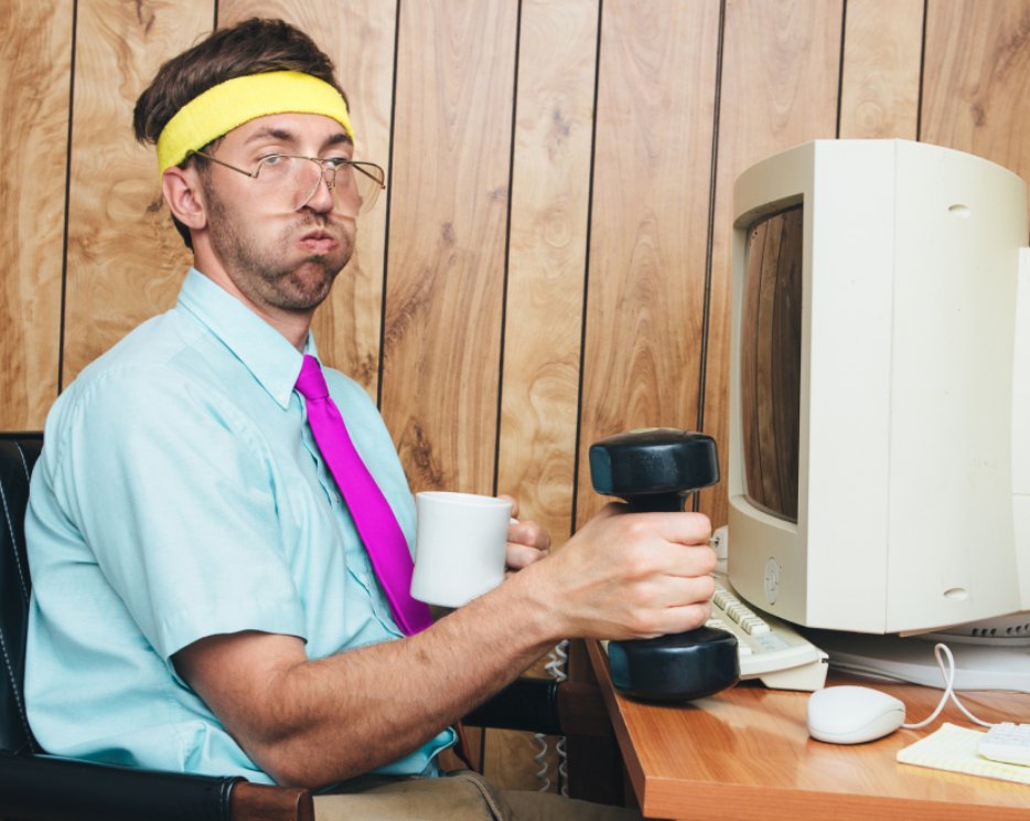 Sportlicher Mann situt vor dem Computer mit einer Hantel und einem Kafee in der Hand